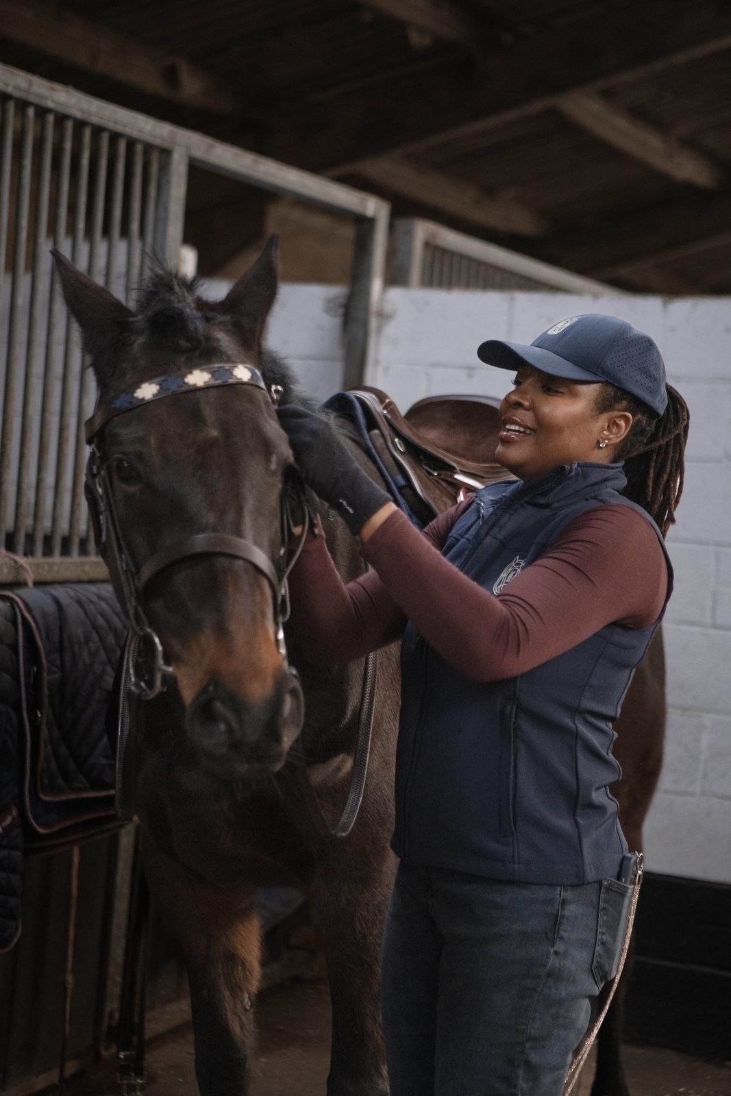 Founder adjusting the saddle on an Asset in the stable